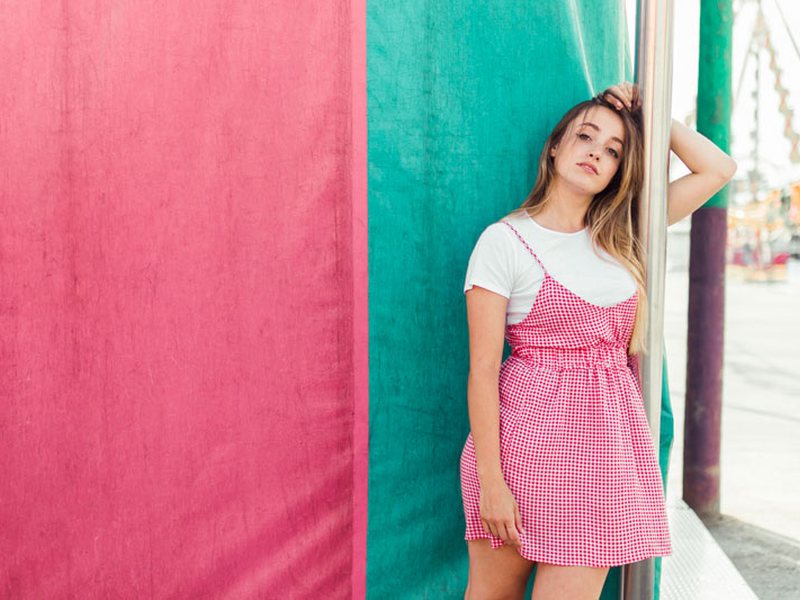 Woman in a pink dress leaning against a colorful wall