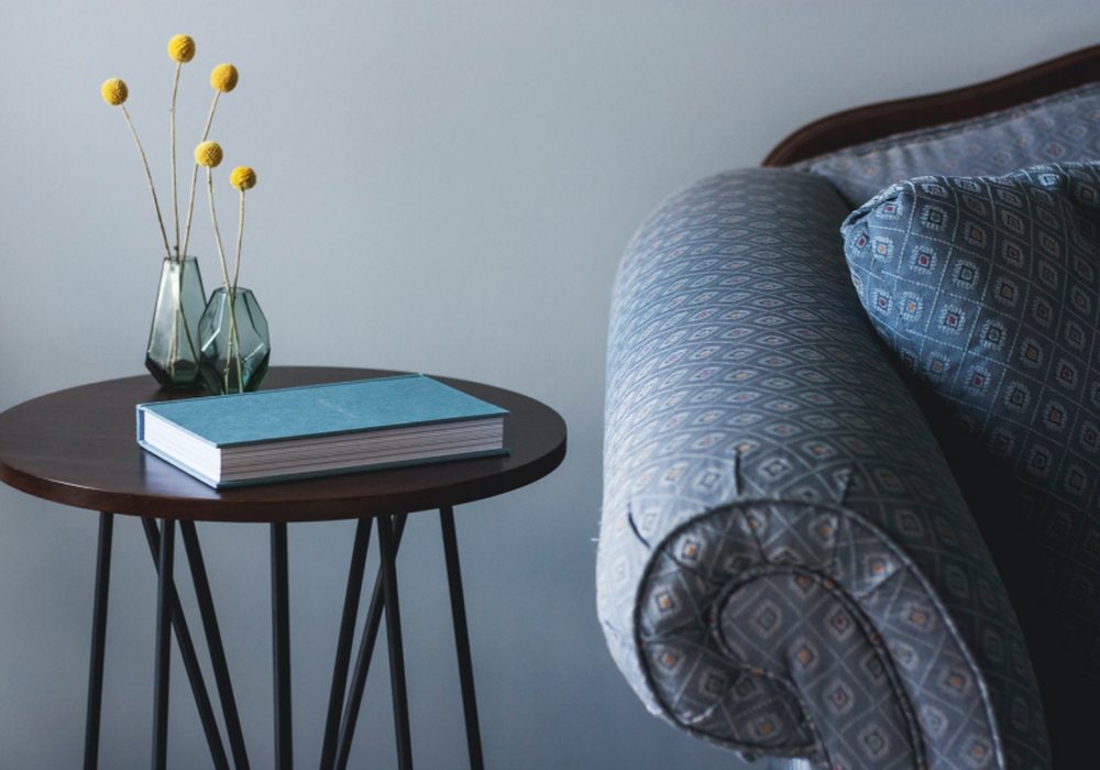Side table with a book beside a soft armchair